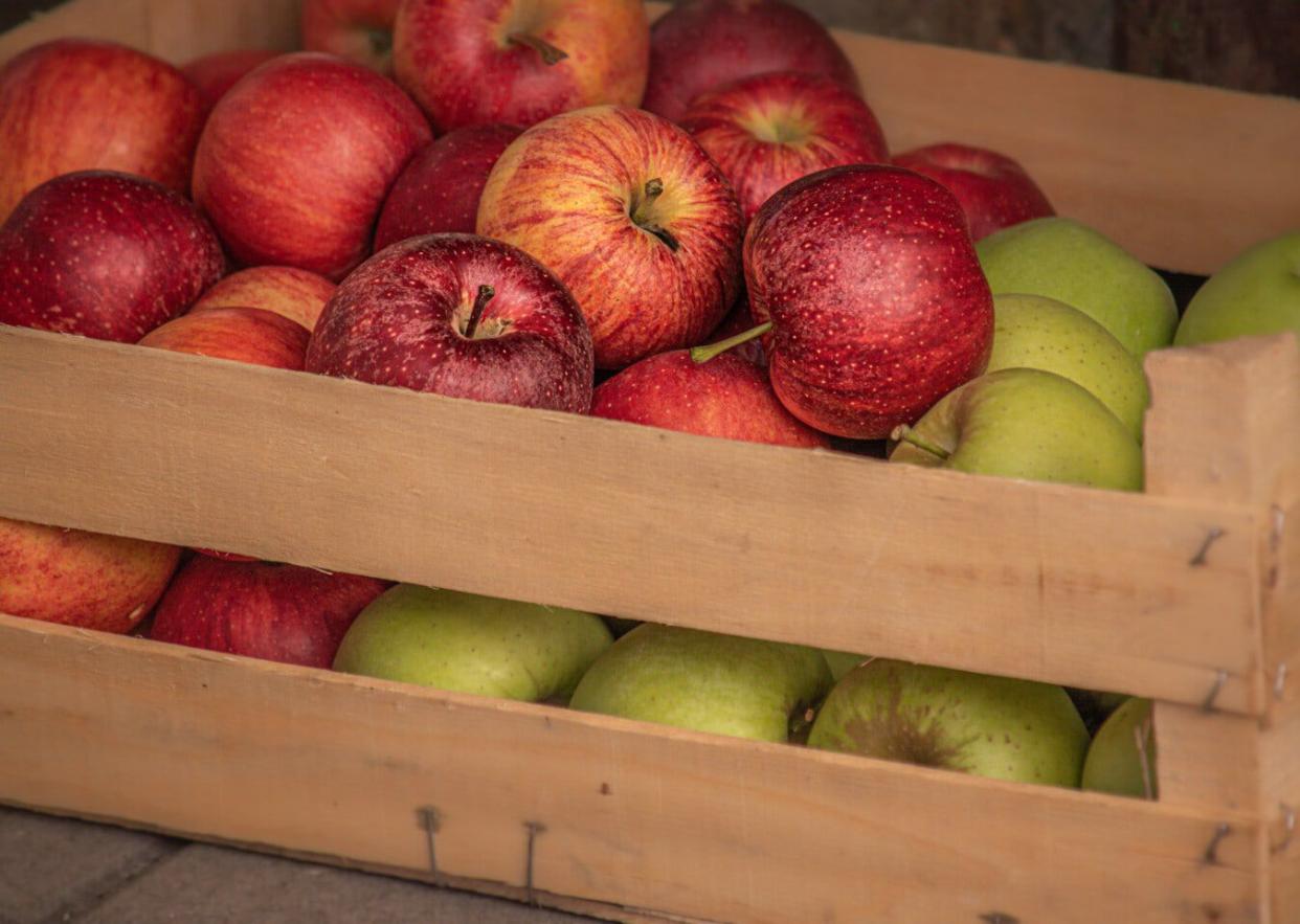 Wooden crate of green and red apples.