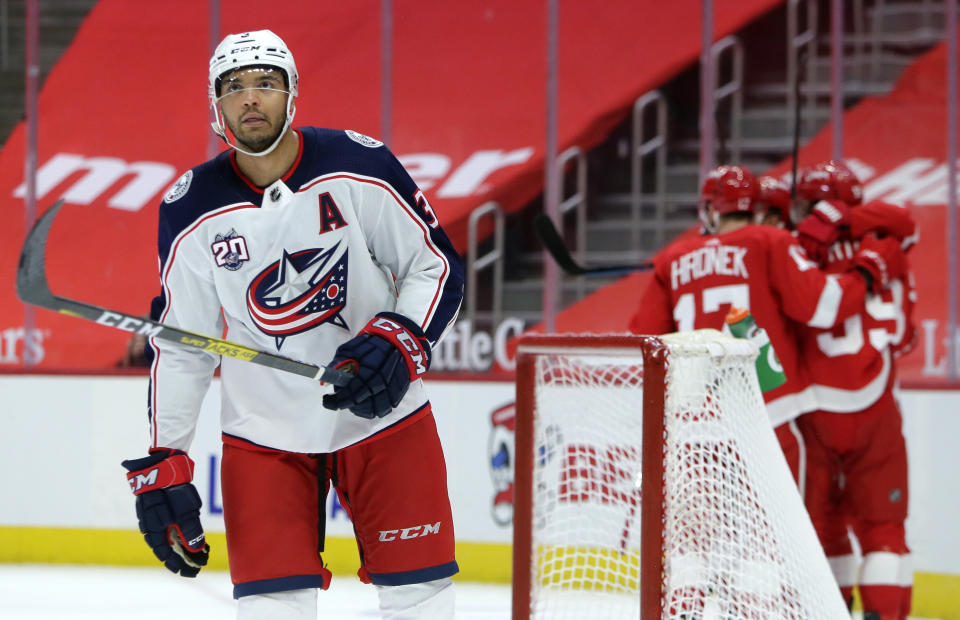 Columbus Blue Jackets defenseman Seth Jones, left, skates away as Detroit Red Wings left wing Tyler Bertuzzi, right, celebrates his game-winning goal with Filip Hronek and other teammates during overtime of an NHL hockey game Tuesday, Jan. 19, 2021, in Detroit. (AP Photo/Duane Burleson)