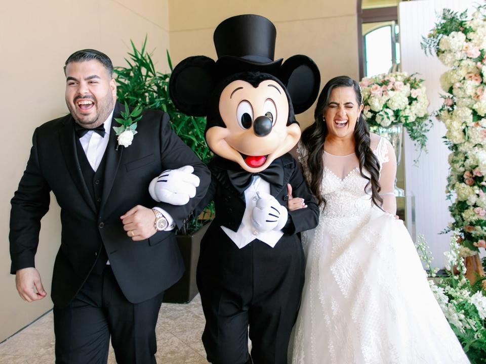 stephanie and her husband posing with mickey mouse at their disney wedding