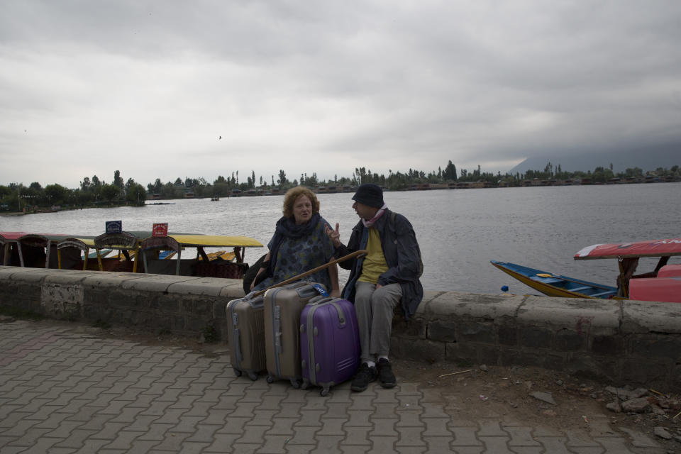 An Italian couple wait for their taxi as they prepare to leave Srinagar, Indian controlled Kashmir, Saturday, Aug. 3, 2019. A government order in Indian-administered Kashmir on Friday asked tourists and Hindu pilgrims visiting a Himalayan cave shrine "to curtail their stay" in the disputed territory, citing security concerns and intensifying tensions following India's announcement it was sending more troops to the region. (AP Photo/ Dar Yasin)