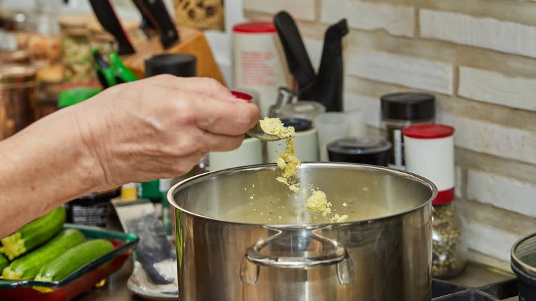 person adding powder to pot