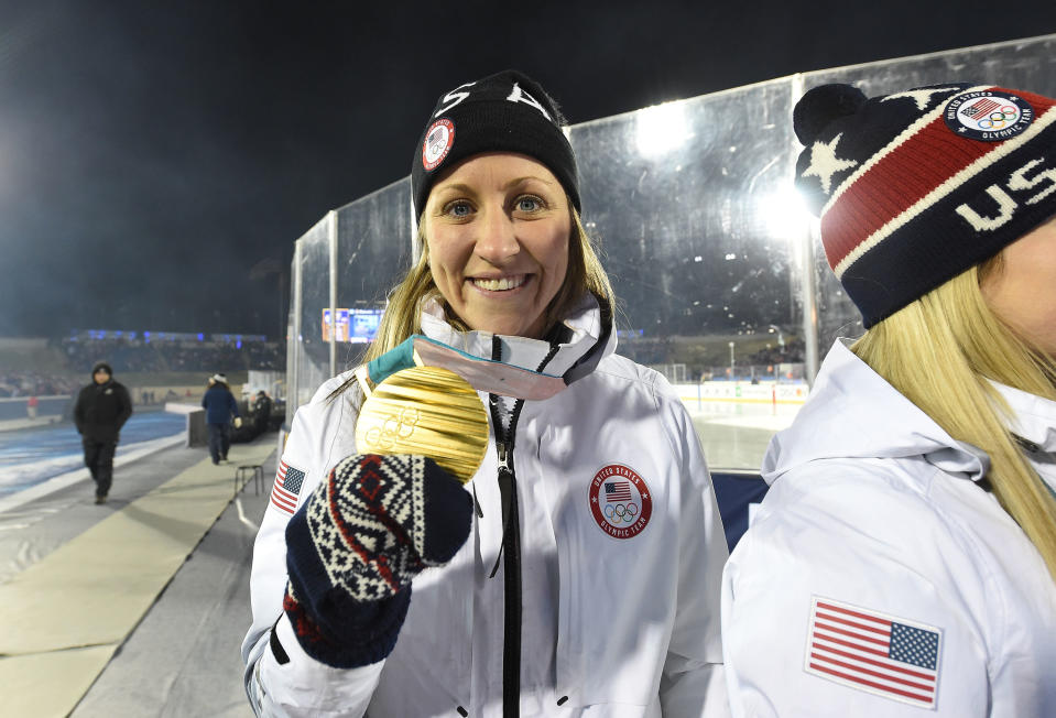 Meghan Duggan of the 2018 United States Women's Hockey Team holds up her gold medal during a ceremony.