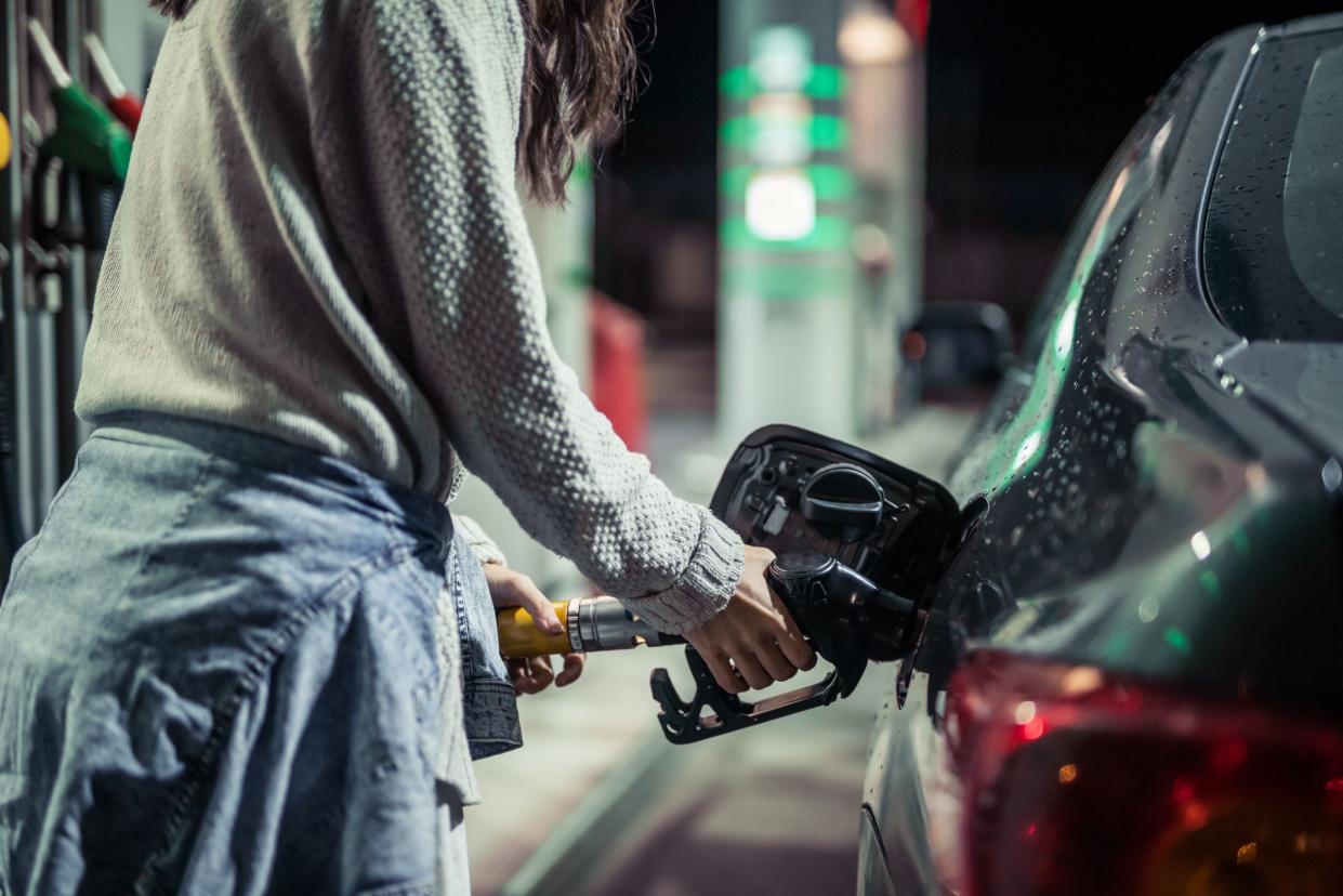 Young woman refueling car with gasoline on the gas station