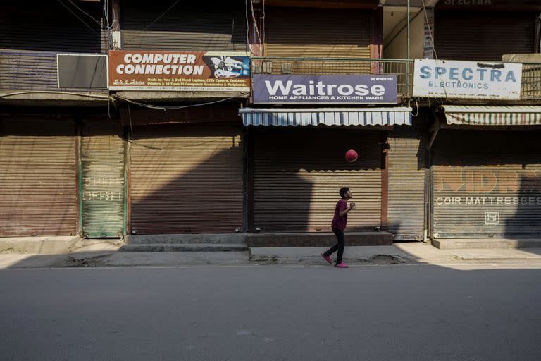 En absoluta soledad, un niño juega con una pelota en Kashmir, India.