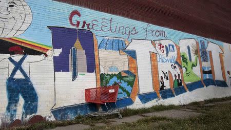 An abandoned shopping cart is seen against a "Greetings from Detroit" mural on the side of a building in a once vibrant neighborhood in Detroit, Michigan, December 3, 2015. REUTERS/Rebecca Cook