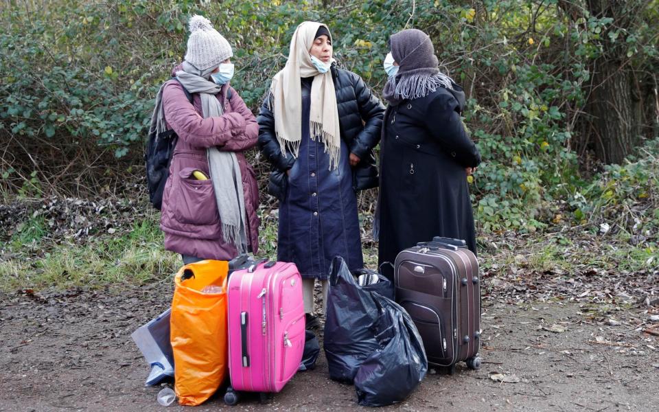 Three women with their belongings are seen at a makeshift migrant camp near Calais - Johanna Geron/Reuters