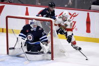 Florida Panthers' Matthew Tkachuk (19) carries the puck behind Winnipeg Jets goaltender Connor Hellebuyck (37) during the first period of an NHL hockey game Tuesday, Dec. 6, 2022, in Winnipeg, Manitoba. (Fred Greenslade/The Canadian Press via AP)