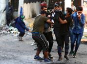 Demonstrators carry away a boy affected by tear gas during ongoing anti-government protests in Baghdad