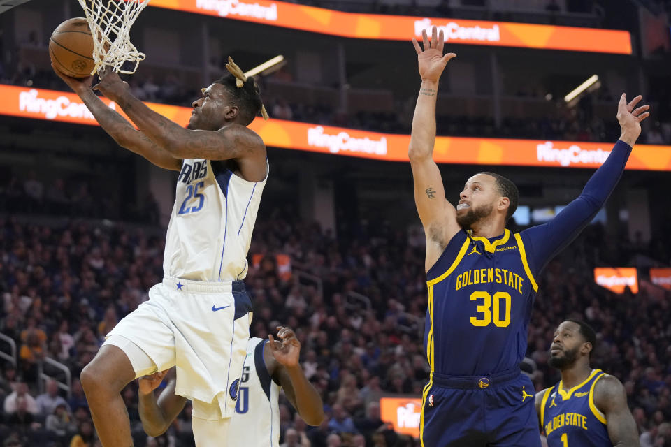 Dallas Mavericks forward Reggie Bullock (25) shoots against Golden State Warriors guard Stephen Curry (30) during the first half of an NBA basketball game in San Francisco, Saturday, Feb. 4, 2023. (AP Photo/Jeff Chiu)