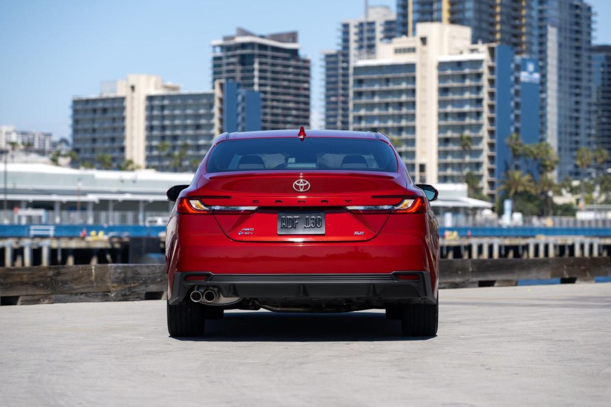 a red car on a road with buildings in the background