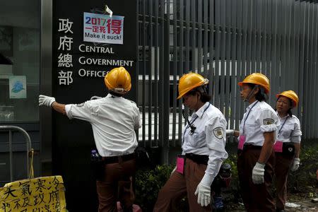 Security guards try to remove a pro-democracy placard displayed outside the government headquarters in Hong Kong, China June 24, 2015. REUTERS/Bobby Yip