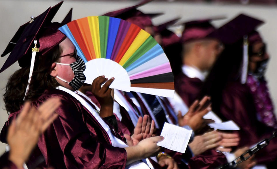 A student uses a colorful fan for shade on a hot day during the Mount Sac graduation at Hilmer Lodge Stadium in Walnut, Calif., Friday, June 11, 2021. (Keith Birmingham/The Orange County Register via AP)