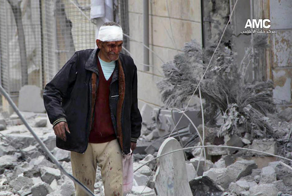 This Tuesday, March. 18, 2014 photo provided by the anti-government activist group Aleppo Media Center (AMC), which has been authenticated based on its contents and other AP reporting, a Syrian man, injured by a government airstrike, walks outside a damaged building in Aleppo, Syria. Activists said Syrian warplanes and helicopter gunships carried out several air raids in the northern province of Aleppo on Tuesday killing and wounding a number of people. (AP Photo/Aleppo Media Center, AMC)