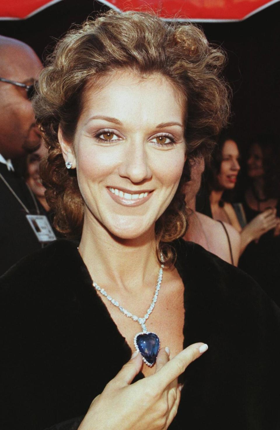 Celine Dion holds a replica of the blue diamond which was aboard the Titanic as she arrives for the 70th Annual Academy Awards