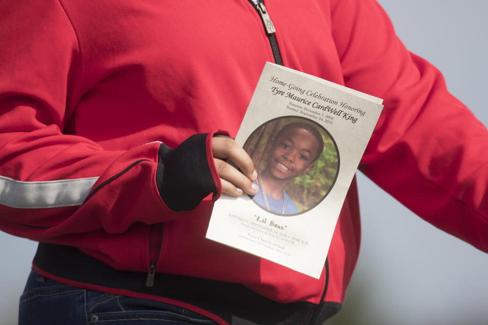 FILE - In this Sept. 24, 2016, file photo, a funeral service card bearing the likeness of Tyre King is carried by a mourner in Columbus, Ohio. The white Ohio police officer who killed 13-year-old King argued in a federal court filing Wednesday, Feb. 17, 2021, that he used reasonable force and race wasn't a factor in the shooting of the Black teenager. Columbus Officer Bryan Mason shot Tyre in 2016 while responding to a reported armed robbery. (AP Photo/John Minchillo, File)