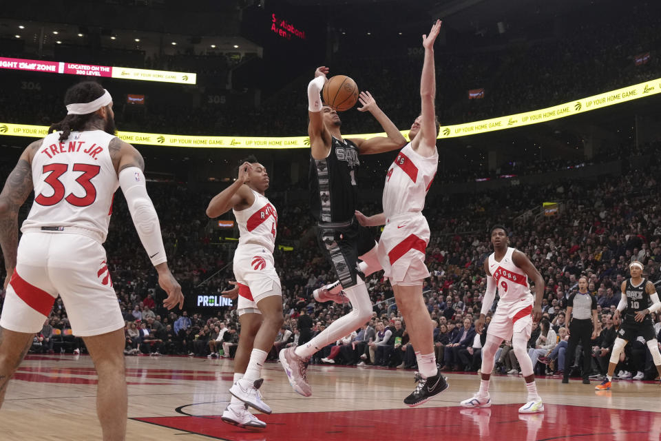 San Antonio Spurs center Victor Wembanyama (1) tries to shoot against Toronto Raptors' Jakob Poeltl, center right, during first-half NBA basketball game action in Toronto, Monday Feb. 12, 2024. (Chris Young/The Canadian Press via AP)