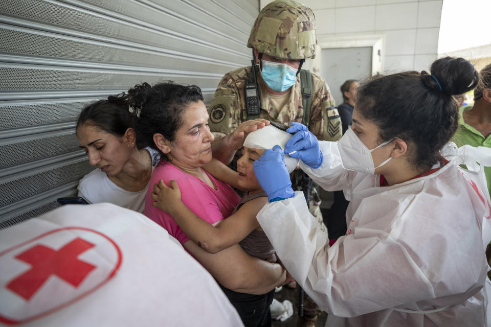 A Syrian woman and her son are cared for after being injured by stones thrown by members of the Christian rightwing Lebanese Forces group, who were attacking Syrian voters heading to their embassy to vote in the Syrian presidential election, in the town of Zouk Mosbeh, north of Beirut, Lebanon, Thursday, May 20, 2021. Mobs of angry Lebanese men attacked buses and cars carrying Syrians expatriates and those who fled the war heading to the Syrian embassy in Beirut on Thursday, protesting against what they said was an organized vote for President Bashar Assad. (AP Photo/Hassan Ammar)