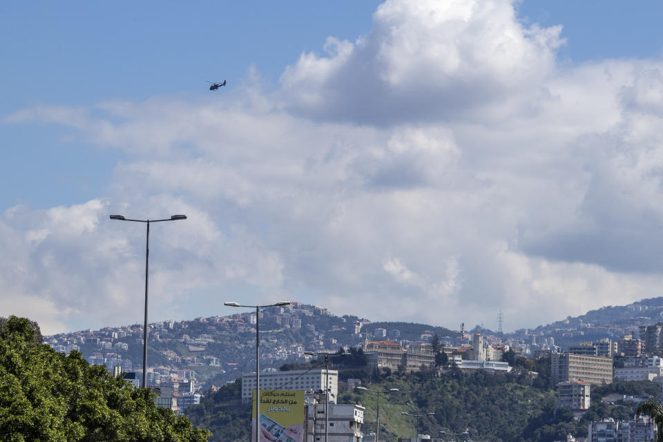 A Lebanese army helicopter flies over east Beirut, after flying lower over neighborhoods using loudspeakers to urge people to stay home unless they have an emergency, in Beirut, Lebanon, Sunday, March 22, 2020. (AP Photo/Hassan Ammar)