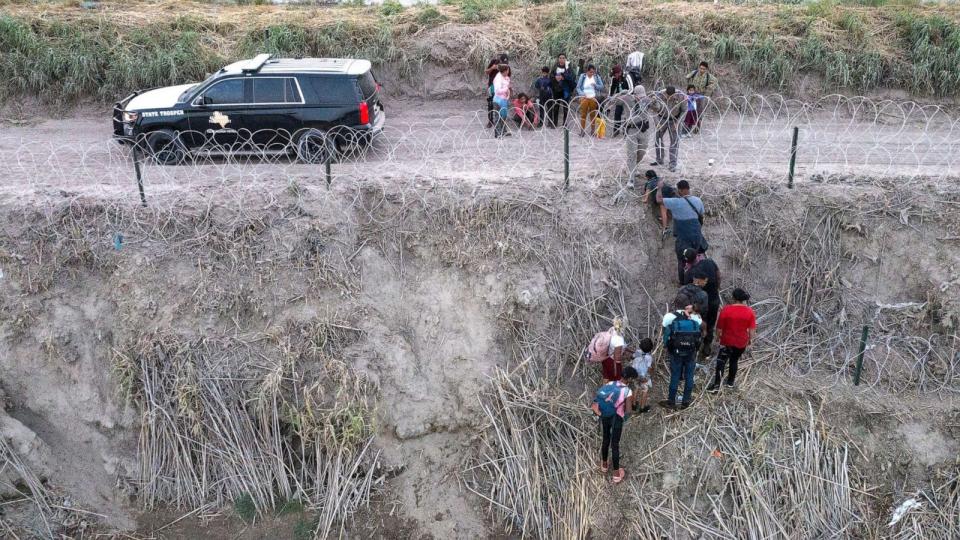 PHOTO: In this July 27, 2023, file photo, Texas Department of Public Safety (DPS) troopers pull migrants from under concertina wire after they crossed the Rio Grande river from Mexico into Eagle Pass, Texas. (Adrees Latif/Reuters, FILE)