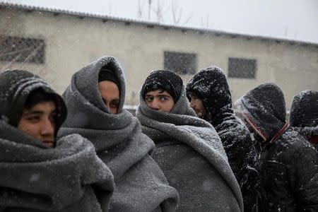 Migrants wait in line to receive free food during a snowfall outside a derelict customs warehouse in Belgrade, Serbia January 9, 2017. REUTERS/Marko Djurica