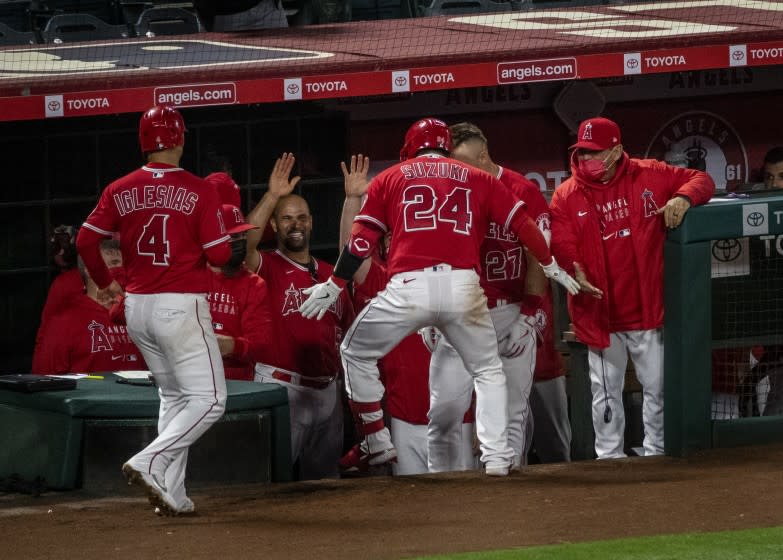 ANAHEIM, CA - APRIL 20, 2021: Los Angeles Angels catcher Kurt Suzuki (24) is congratulated art the dugout after hitting a 2-run home run against Texas Rangers starting pitcher Taylor Hearn (52) in the 7th inning at Angel Stadium on April 20, 2021 in Santa Ana California.(Gina Ferazzi / Los Angeles Times)