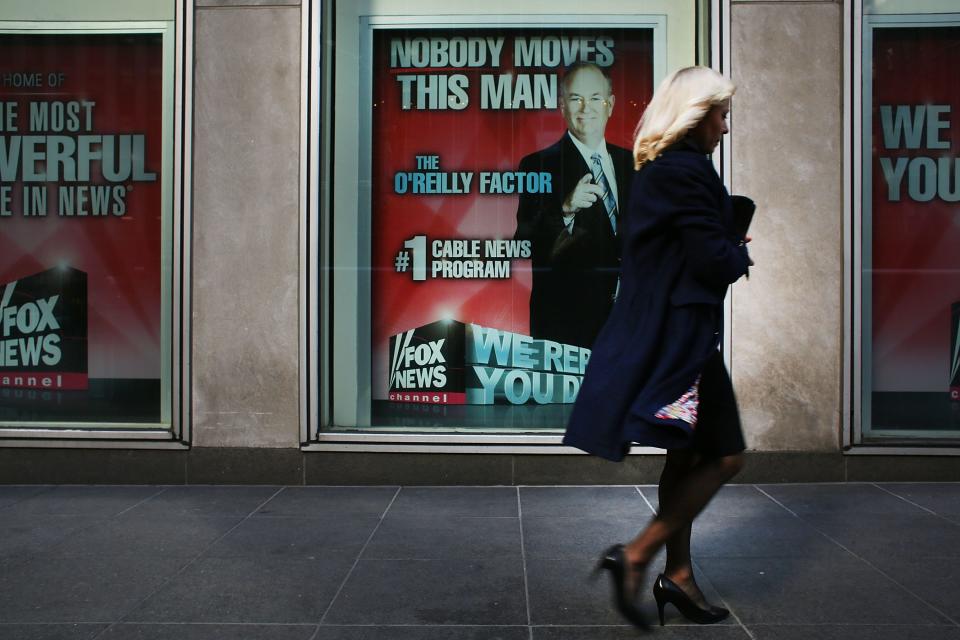 A woman walks by an ad displayed in a window.