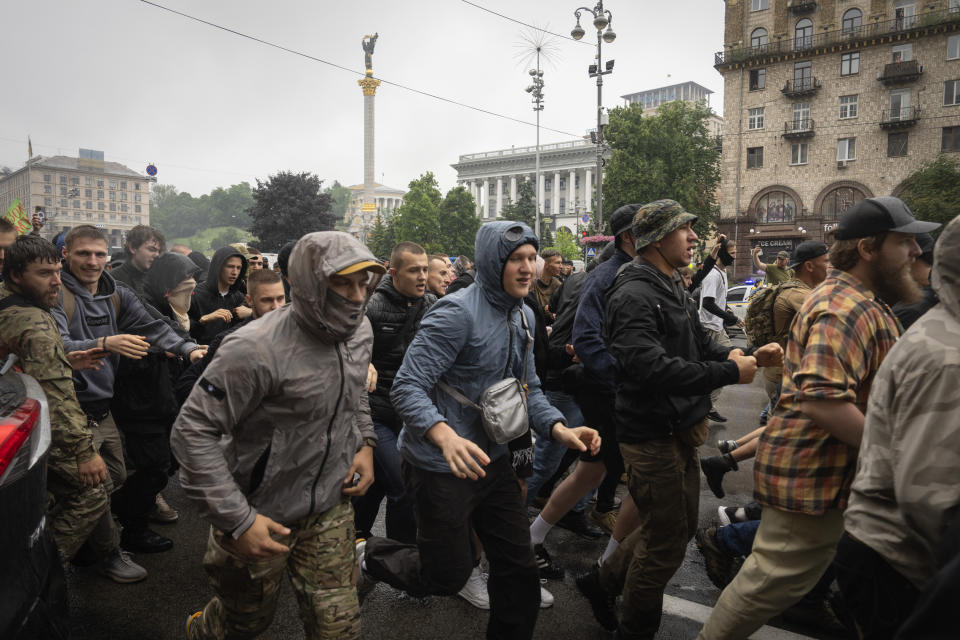 Ultra-right activists run along the city main avenue protesting the annual Gay Pride parade, under the protection of riot police in Kyiv, Ukraine, Sunday, June 16, 2024. Several hundred LGBT Ukrainian servicemen and other protesters joined the pride march in central Kyiv Sunday seeking legal reforms to allow people in same-sex partnerships to take medical decisions for wounded soldiers and bury victims of the war that extended across Ukraine more than two years ago. (AP Photo/Efrem Lukatsky)