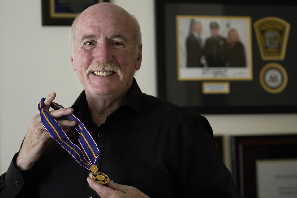 Retired Watertown police Sgt. Jeffrey Pugliese stands for a photograph, Tuesday, June 1, 2021 at his home in Watertown, Mass., as he displays the Medal of Valor that was awarded to him in February 2015 by then Vice President Joe Biden and Attorney General Eric Holder during ceremonies in Washington. Pugliese, who became a national hero in 2013 when he tackled one of the Boston Marathon bombers, retired on Monday, May 31, 2021, after more than 41 years on the force. (AP Photo/Steven Senne)