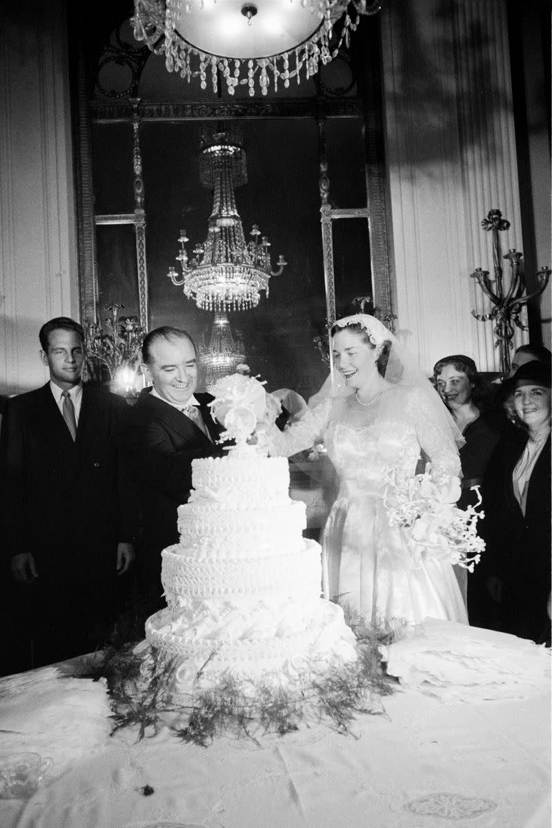 <p> Senator Joseph McCarthy spared no expense for his 1953 wedding to Jean Kerr. The couple tied the knot in Washington D.C. with over 1,000 guests in attendance. Kerr's dress featured a sweetheart neckline and lace detailing on the bodice and sleeves, which she paired with a tulle and lace veil. </p>
