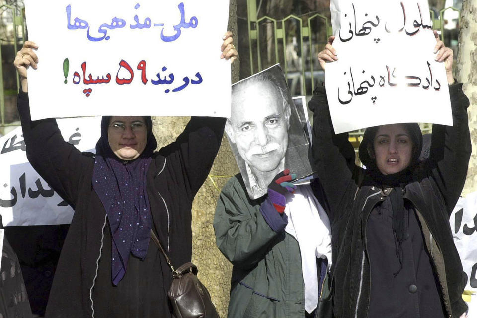 FILE - Narges Mohammadi, wife of dissident Taqi Rahmani, right, and Farzaneh Roustaei, wife of Reza Raeis Tousi, left, hold signs while another protestor holds a photo of dissident reformist Habibollah Peyman, center, during a protest outside the court building in Tehran, Tuesday, Jan. 8, 2002, to protest against the closed trial of fifteen prominent political dissidents charged with plotting to overthrow the Islamic establishment. The Nobel Peace Prize has been awarded to Narges Mohammadi for fighting oppression of women in Iran. The chair of the Norwegian Nobel Committee announced the prize Friday, Oct. 6, 2023 in Oslo. Writing on the sign at left read, "Dissidents in the military prison" while the sign at right reads, "Hidden prison, hidden trial". (AP Photo/Hasan Sarbakhshian, File)