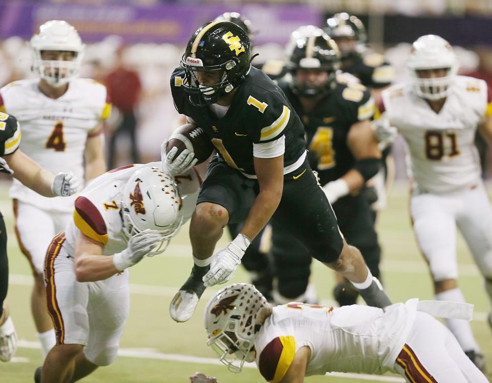 Southeast Polk running back CJ Phillip (1) jumps over Ankeny cornerback Jacob Mohrfeld (3) and linebacker Angelo Wernau (7) for a touchdown during the third quarter of the Rams' 49-21 victory over the Hawks in the Class 5A Iowa High School football championship game at UNI-Dome on Friday, Nov. 17, 2023, in Cedar Falls, Iowa.