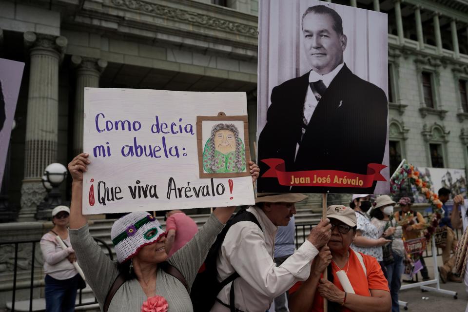 Protestors hold a photo of former Guatemalan president Juan Jose Arevalo and a sign that reads in Spanish "Like my granny used to say: Viva Arevalo!" during a march supporting democracy in Guatemala City, Sunday, Aug. 13, 2023. Arevalo's son Bernardo is the current presidential candidate for the Seed movement party and faces rival Sandra Torres of the UNE party in an Aug. 20 runoff election.