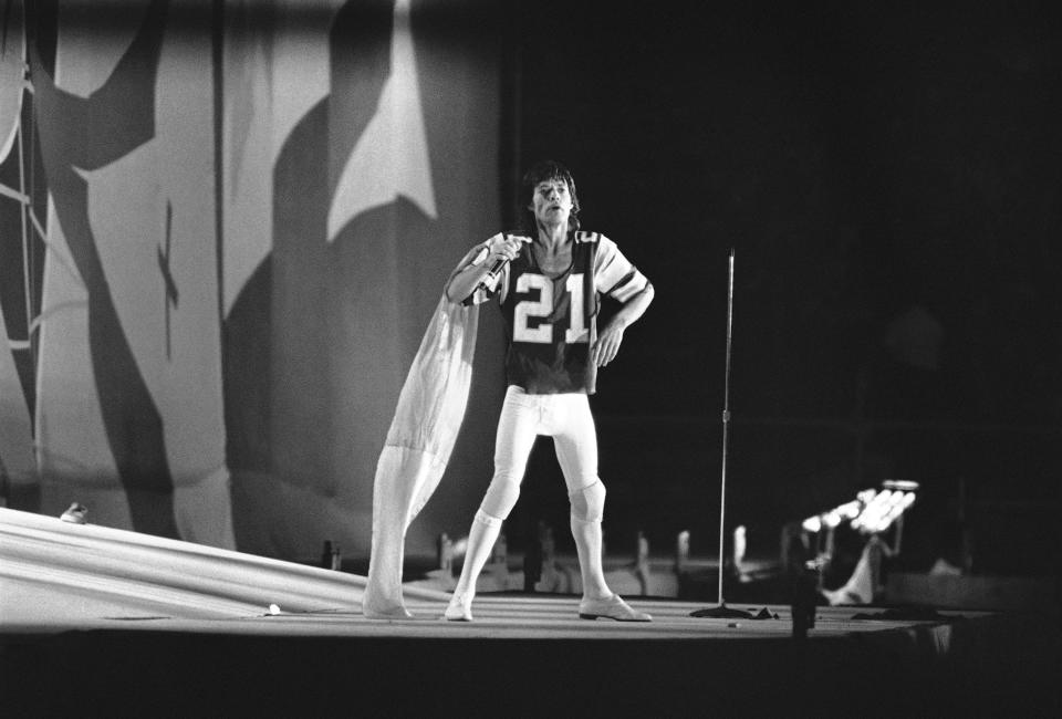 Rolling Stones singer Mick Jagger, a cape trailing behind him and wearing an John Sciarra Eagles jersey, performs during a Stones concert in front of nearly 90,000 fans in the Los Angeles Coliseum, Oct. 10, 1981.