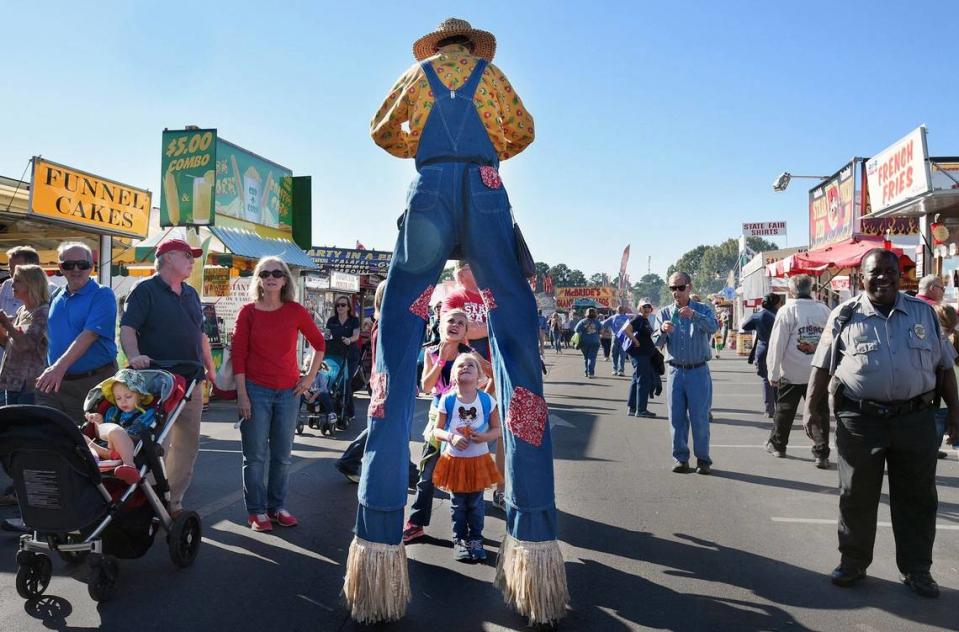 Opening day visitors to the NC State fair look up at a balloon animal maker on stilts on the midway in Raleigh, Thursday, October 15, 2015. Chuck Liddy/File photo