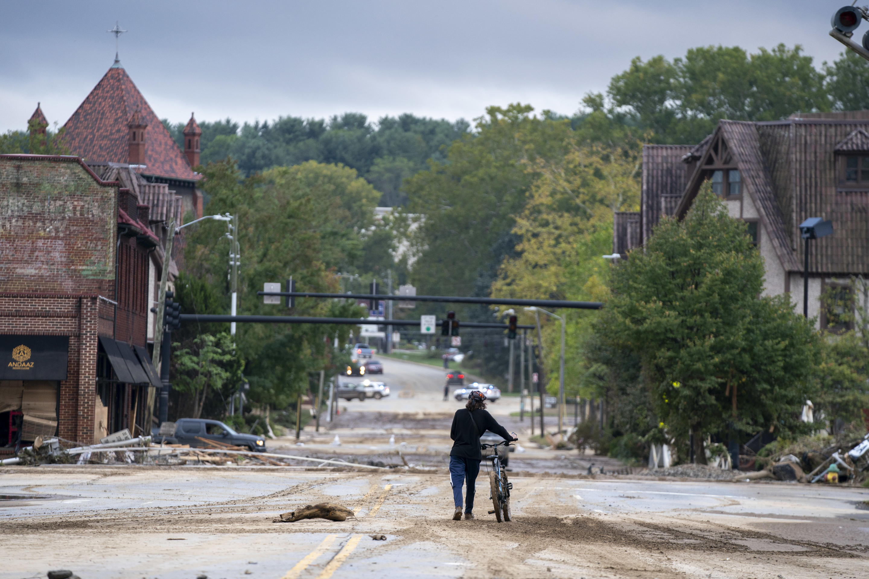 A person rides a bicycle along a damaged street in Biltmore Village, North Carolina.