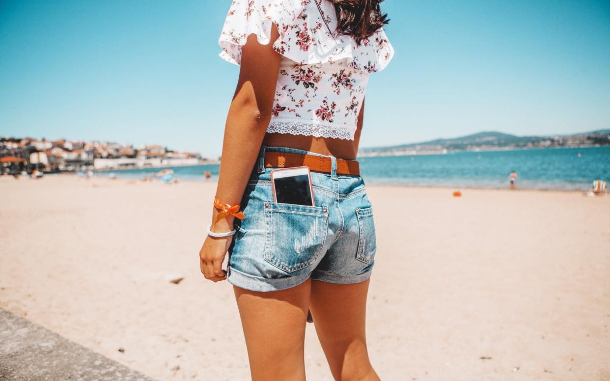 woman in jeans shorts with the phone in pocket - Getty Images Contributor