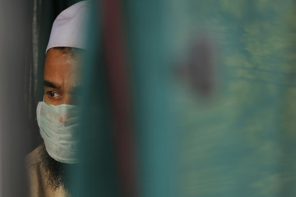 FILE - In this April 21, 2020, file photo, a Muslim man, among 29 people arrested by Indian authorities, sits inside an ambulance before being taken to a prison from a quarantine center in Prayagraj, India. Muslims in India are being stigmatized after the government blamed an Islamic missionary meeting for a surge in coronavirus cases. Experts who have studied previous epidemics warn that the stigma could hamper efforts to stop the contagion and prevent many from getting themselves tested. (AP Photo/Rajesh Kumar Singh, File)