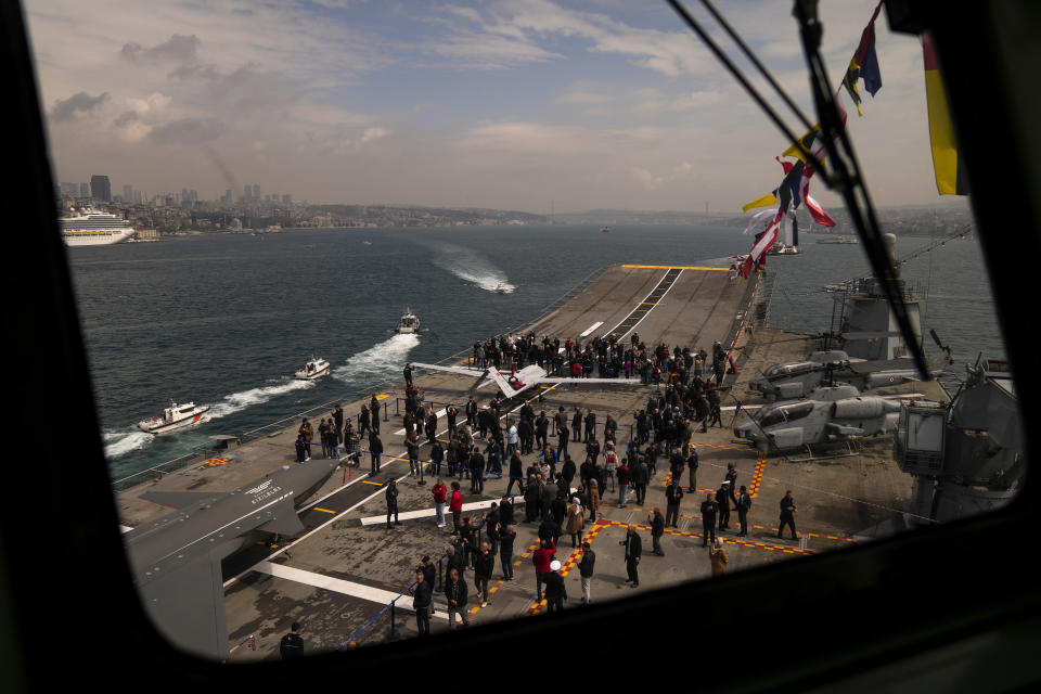 People stand next to unmanned combat aerial vehicles (UCAV) Bayraktar TB3, right, and Bayraktar Kizilelma on board the Turkish amphibious assault ship TCG Anadolu L400, anchored in Istanbul, Turkey, Thursday, April 20, 2023. (AP Photo/Francisco Seco)