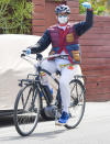 <p>Robert Downey Jr. shows a sign of solidarity as he rides his bike on Monday in Malibu.</p>