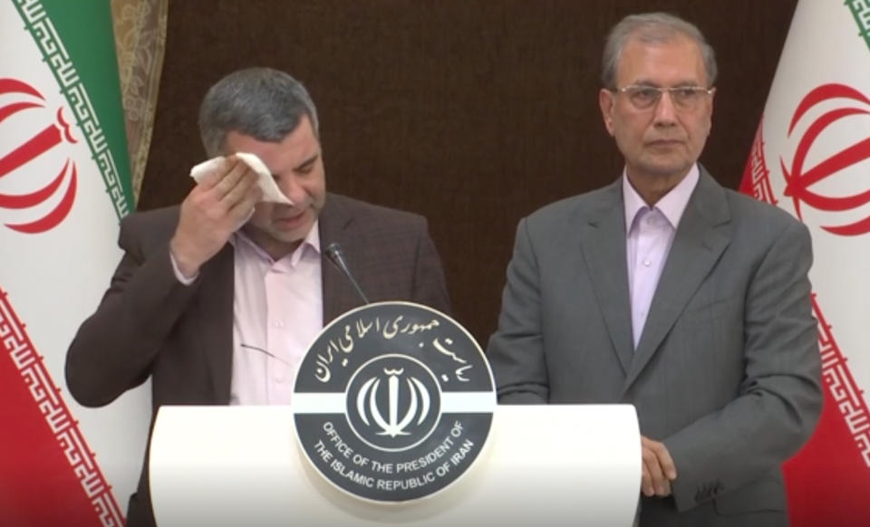 In this Monday Feb. 24, 2020 image made from video the head of Iran's counter-coronavirus task force, Iraj Harirchi, left, wipes his face during a press briefing with government spokesman Ali Rabiei, in Tehran, Iran. Harirchi, has tested positive for the virus himself, authorities announced Tuesday, amid concerns the outbreak may be far wider than officially acknowledged. The announcement regarding Harirchi came after the news conference seeking to minimize the danger posed by the outbreak. (APTN via AP)