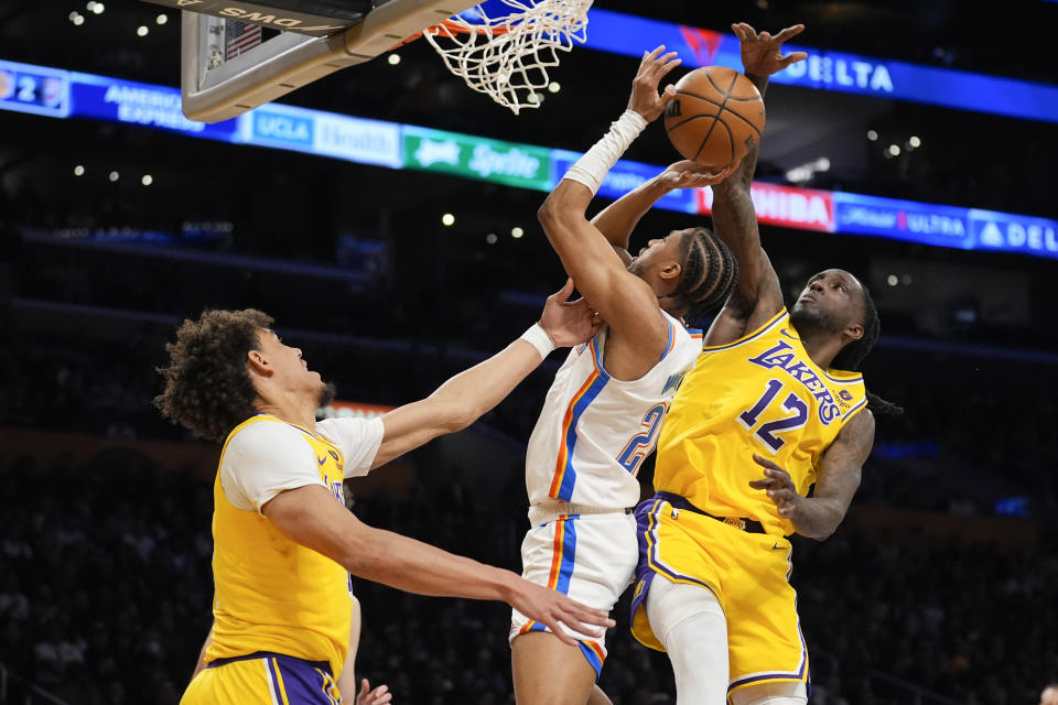 Los Angeles Lakers forward Taurean Prince (12) blocks a shot by Oklahoma City Thunder guard Aaron Wiggins, center, during the first half of an NBA basketball game Monday, March 4, 2024, in Los Angeles. (AP Photo/Marcio Jose Sanchez)