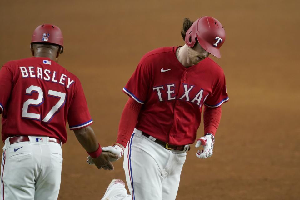 Texas Rangers third base coach Tony Beasley (27) congratulates Jonah Heim on his solo home run in the sixth inning of a baseball game against the Seattle Mariners in Arlington, Texas, Friday, July 30, 2021. (AP Photo/Tony Gutierrez)