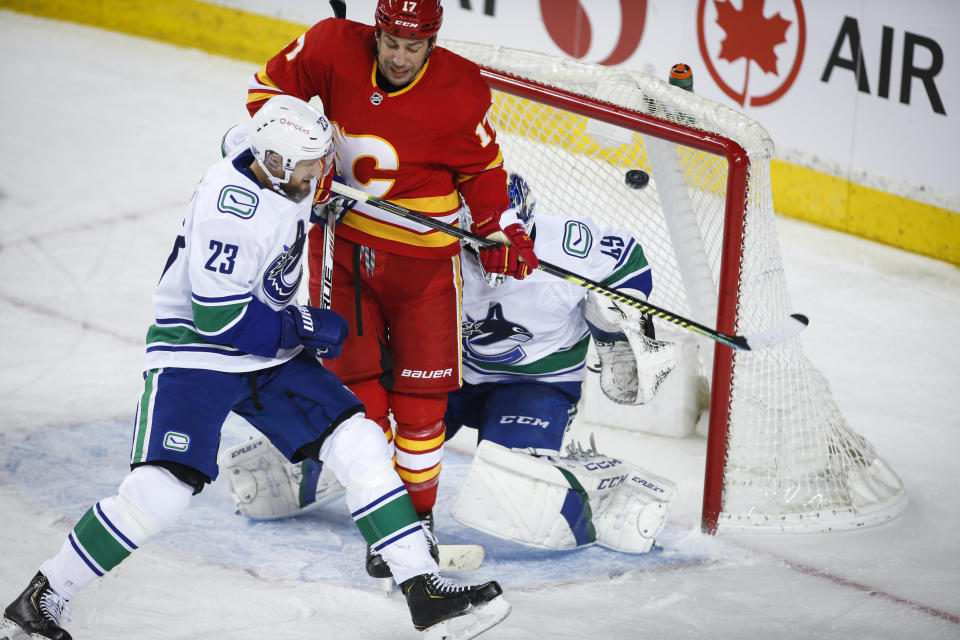 Vancouver Canucks' Alexander Edler, left, looks on as goalie Braden Holtby, right, gives up a goal, while Calgary Flames' Milan Lucic tries to get out of the way during the second period of an NHL hockey game Saturday, Jan. 16, 2021, in Calgary, Alberta. (Jeff McIntosh/The Canadian Press via AP)