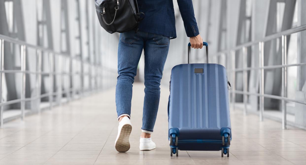 Man walks through airport with luggage. (Getty Images)