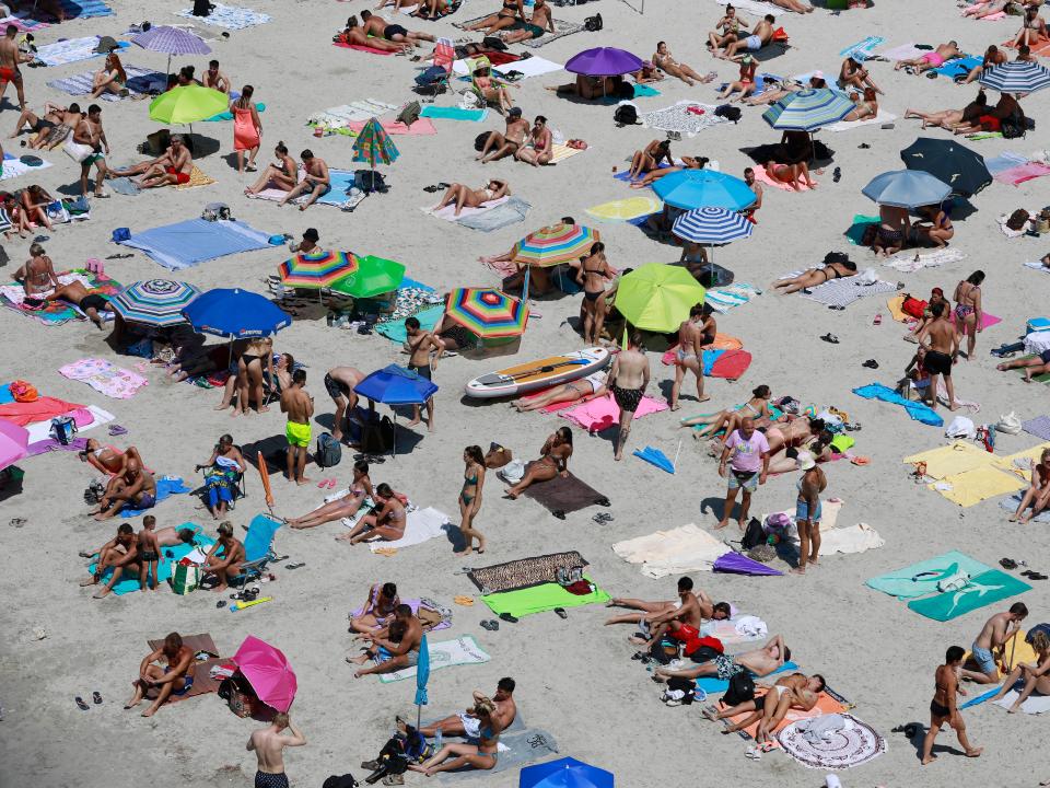 Crowds of people sunbathing in August 2022 at Cala Pi beach in Spain.
