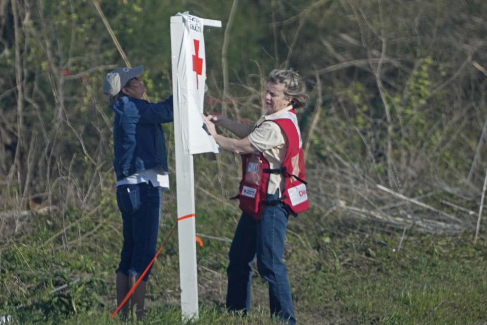 American Red Cross volunteers push through a stiff wind to tape down a directional sign for those Silver City, Miss., residents affected by Friday's tornado and needing assistance, Tuesday, March 28, 2023. (AP Photo/Rogelio V. Solis)