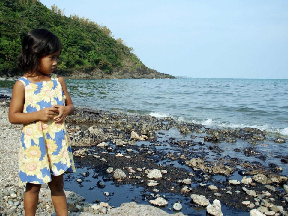 A young girl looks at the coast of Nueva Valencia in Guimaras island blackened by oil spill in August 2006.