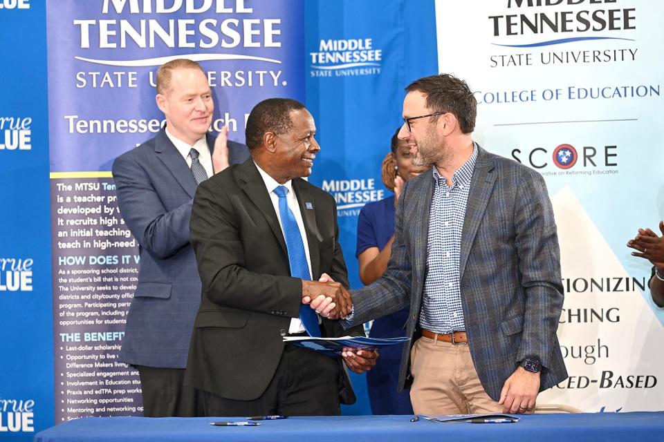 Middle Tennessee State University President Sidney A. McPhee, left, shakes hands with David Mansouri, president and CEO of the State Collaborative on Reforming Education, or SCORE, after signing an agreement to the new Tennessee Teach Back Initiative — an effort to create a teacher pipeline to high-needs school districts — at a ceremony held Monday, May 8, at Homer Pittard Campus School in Murfreesboro, Tenn. Pictured behind them are MTSU alumnus and Murfreesboro City Schools Director Trey Duke, back left, and Neporcha Cone, incoming dean of the MTSU College of Education.