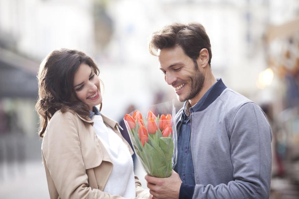 woman offering flowers to a man in the street