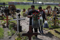 Men carry flowers as family members arrive to decorate the grave of a man who died of suspected COVID-19, in a section of the Municipal Cemetery of Valle de Chalco opened three months ago to accommodate the surge in deaths amid the ongoing new coronavirus pandemic, on the outskirts of Mexico City, Friday, Aug. 7, 2020. Mexico on Thursday jumped above 50,000 recorded deaths from COVID-19, the third-highest death toll in the world, behind only the United States and Brazil. (AP Photo/Rebecca Blackwell)